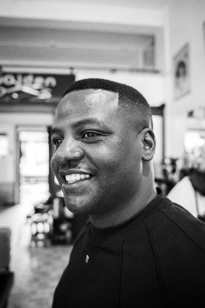 Ben Ozzly smiling at Golden Scissors Salon in Jinja, Uganda